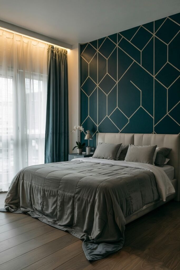 A bedroom wall is painted in deep teal with a geometric pattern of fine lines overlaying it. A bed with grey bedding is placed against the wall, with a modern nightstand, lamp, and orchid plant beside it. Wooden flooring is visible.