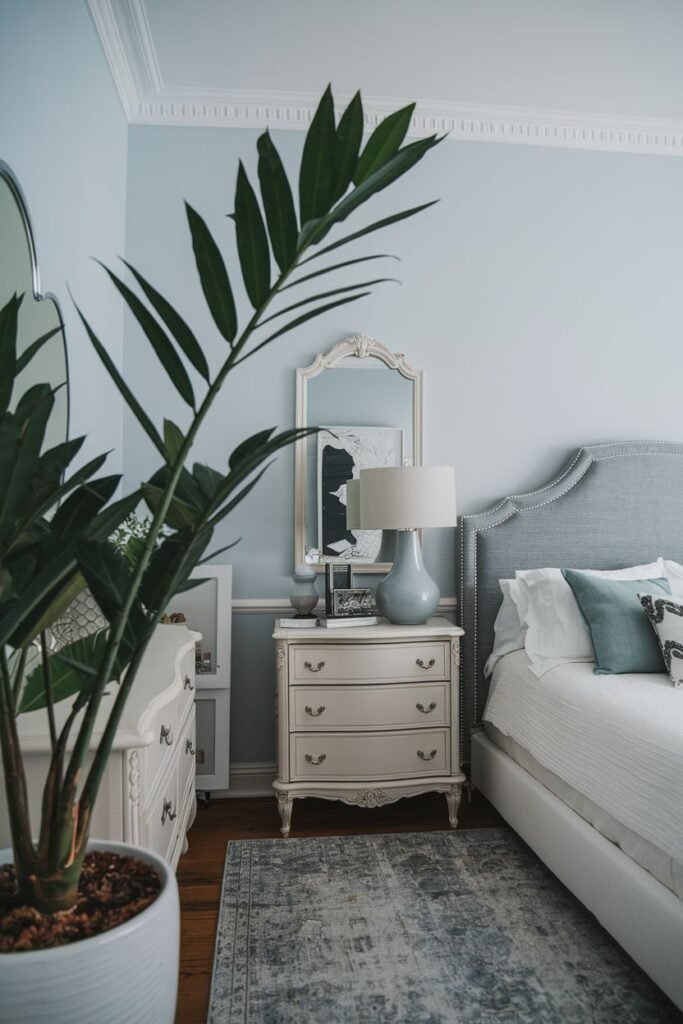 A tall ZZ plant with upright stems in a white pot is positioned next to a bedroom dresser.