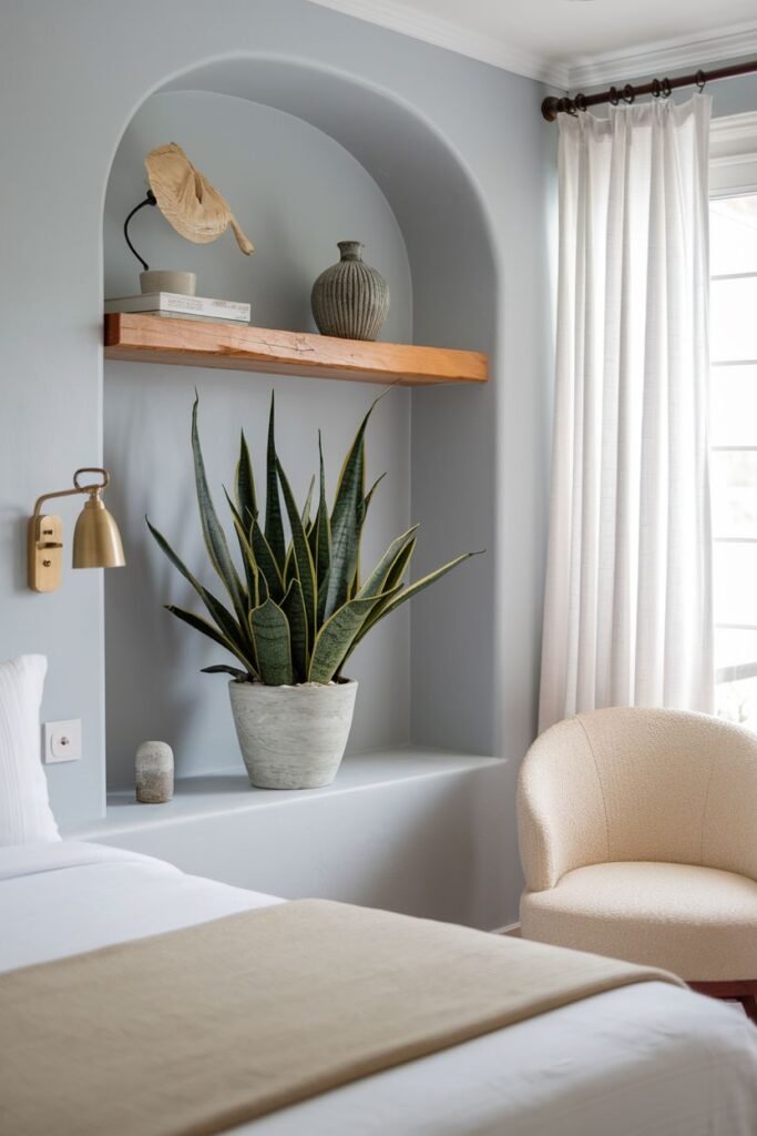 A snake plant in a textured pot is placed within a built-in arched wall niche, functioning as a sculptural element.