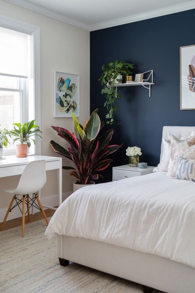 A tall plant with dark red and green leaves in a pot sits against a dark blue accent wall, with trailing plants on a shelf above a desk.