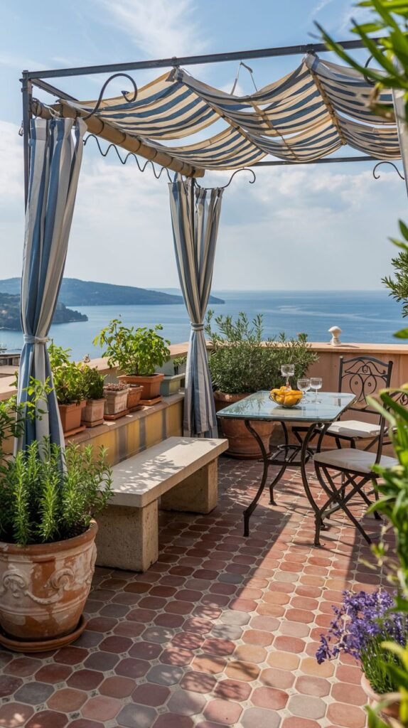 A picturesque and cozy terrace overlooking the sea, featuring a wrought iron table and chairs under a striped awning, with potted plants, creating a modern Mediterranean feel.
