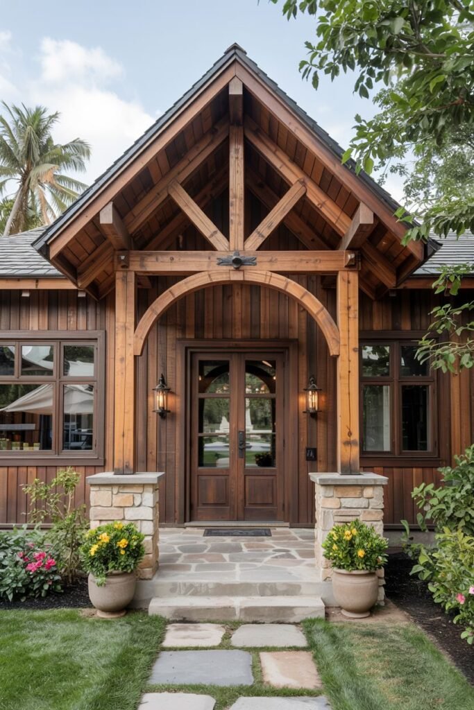 A rustic wooden house with a prominent arched entryway supported by heavy wooden beams and stone pillars. The double wooden doors and warm outdoor lights create a cozy and grand entrance. Potted plants sit near the stone steps, adding a touch of nature.