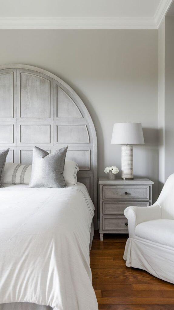 An elegant and clean bedroom featuring a large, semi-circular Grey Headboard with a grid-like paneled design, paired with crisp white bedding.