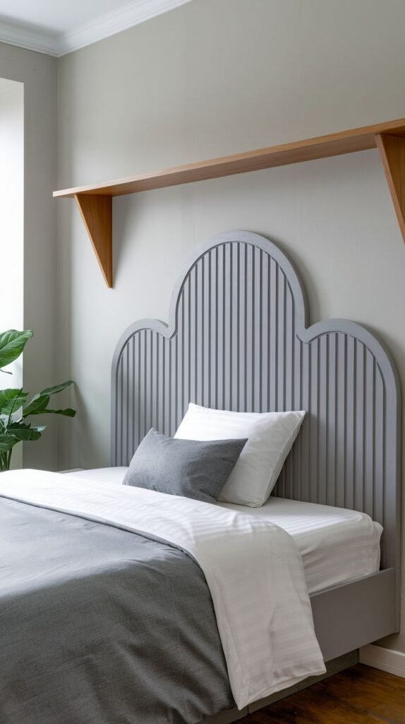 A minimalist and elegant bedroom with a unique cloud-shaped Grey Headboard made of vertical slats, topped with a simple wooden shelf.