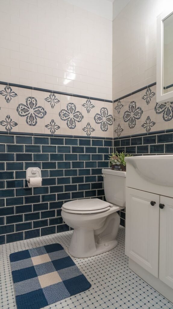 A vibrant half bathroom featuring dark blue subway tiles on the lower walls and a decorative border of blue and white patterned tiles above, topped with white subway tiles. It includes a white toilet and a white vanity with a white sink. A blue and white checkered bath mat is on the patterned white floor.
