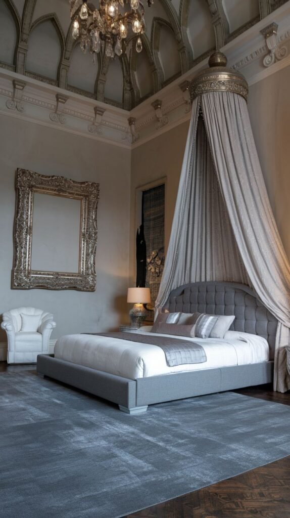 A majestic king bedroom with a soft grey upholstered bed and a unique canopy draped from the ceiling. The room features a large, intricately framed mirror, arched ceiling details, and a crystal chandelier, presenting a refined and serene ambiance.
