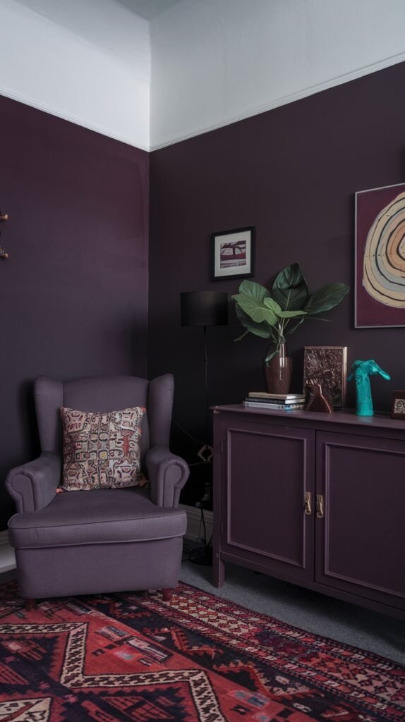 A cozy room with dark purple walls. An armchair in a matching dark purple hue with a patterned pillow sits in the corner. A dark purple credenza is against the wall, adorned with plants and decorative objects. A traditional patterned red and orange rug covers the floor.