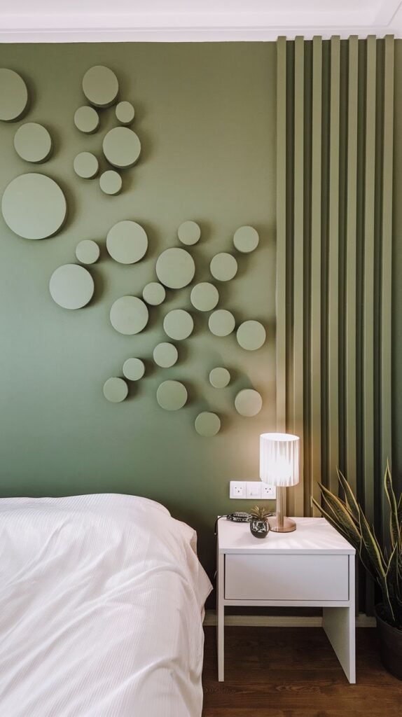 A light green accent wall in a bedroom features an arrangement of varying sized circular reliefs on one side and vertical slats on the other, creating a modern and dynamic design.