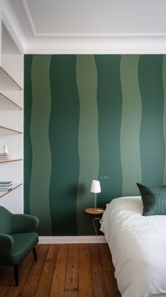 A green accent wall in a bedroom is painted with wavy vertical stripes in two different shades of green, introducing visual interest and a cozy, dynamic space.
