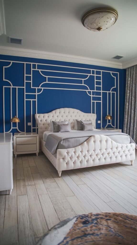 Art Deco Inspired Blue Wall with White Geometric Molding Bedroom with a striking blue accent wall overlaid with intricate white geometric molding in an Art Deco style, framing a large, tufted white bed and set against light wood flooring.