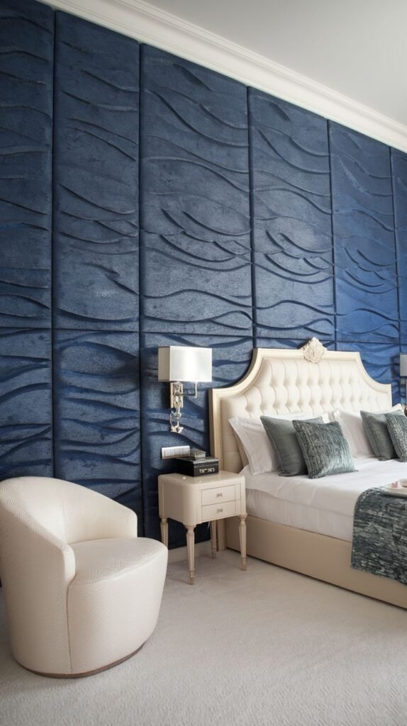 Textured Navy Blue Wave Panel Design Bedroom wall covered in tall, vertical, dimensional panels in dark blue velvet or suede, featuring a prominent, undulating wave texture, contrasting with a tufted cream headboard.