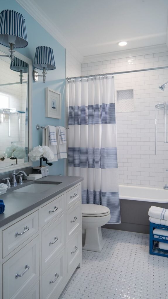 Coastal Small Full Bathroom featuring light blue walls, a white vanity with a gray counter, a blue and white horizontally striped shower curtain, and matching striped lighting sconces.