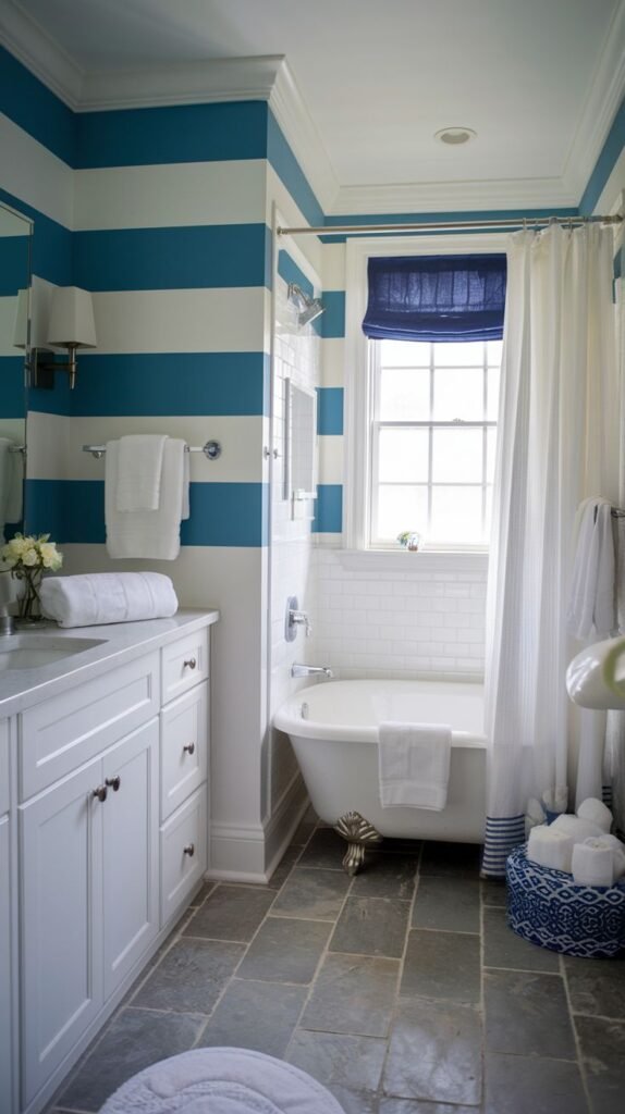 Coastal Small Full Bathroom featuring walls with bold, wide horizontal blue and white stripes, a white claw-foot tub, and large dark gray slate floor tiles.