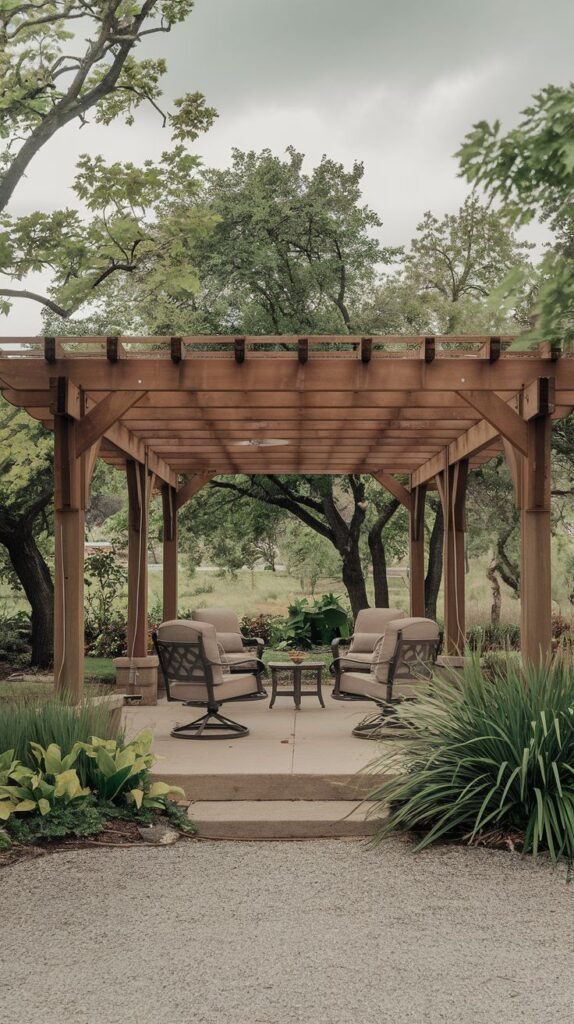 Modern wooden pergola structure with a ceiling fan, covering a concrete patio furnished with four cushioned swivel lounge chairs, set against a backdrop of dense forest and greenery.