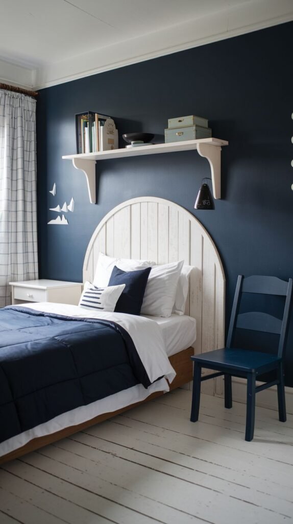 Cozy Small Bedroom For Boys utilizing a dramatic dark navy blue wall color contrasted with a white slatted, rounded headboard and distressed white wood flooring. Dark blue bedding and a matching wooden chair reinforce the blue theme.