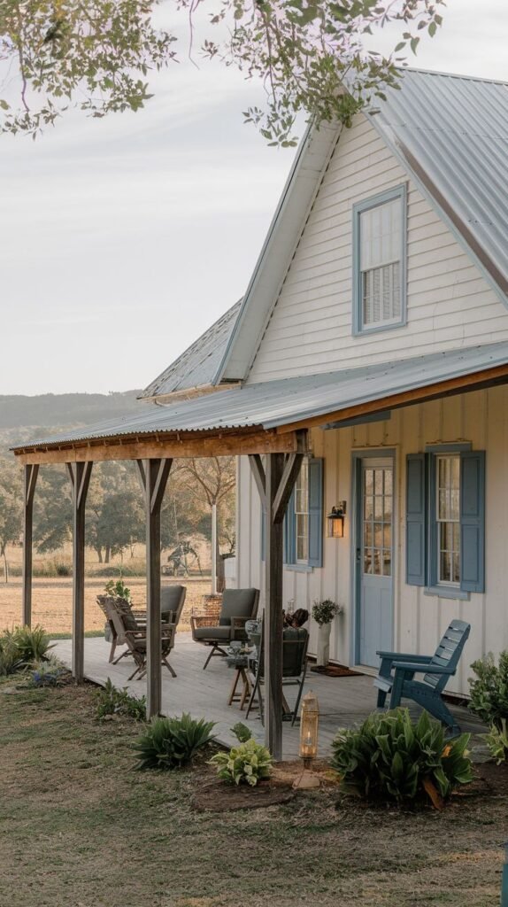 Covered wooden deck porch with a corrugated metal roof and exposed wood supports, attached to a white vertical board house with light blue trim and shutters, featuring mixed outdoor seating.