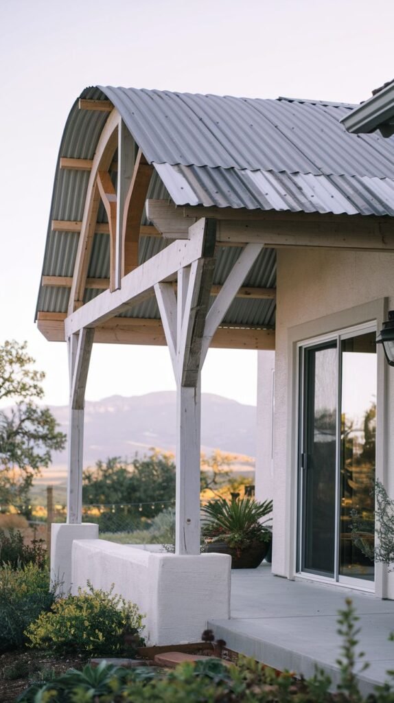Unique patio cover featuring a dramatic curved/vaulted roofline covered in corrugated metal, supported by white wooden columns and exposed interior framing, overlooking a natural landscape.