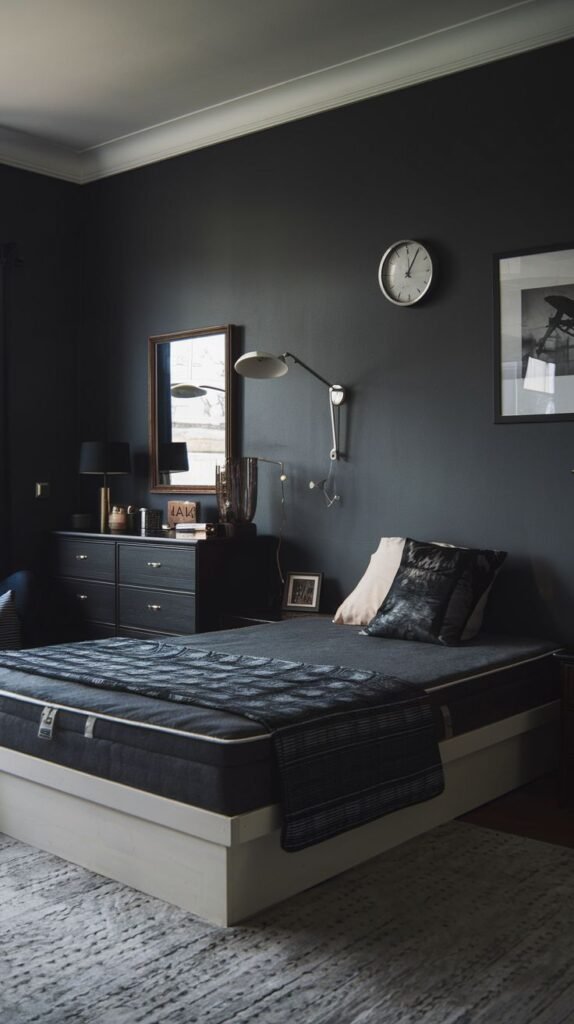 High-contrast Cozy Small Bedroom For Men with matte black walls, a white platform bed base, dark bedding, a dark dresser, and a large circular wall clock.