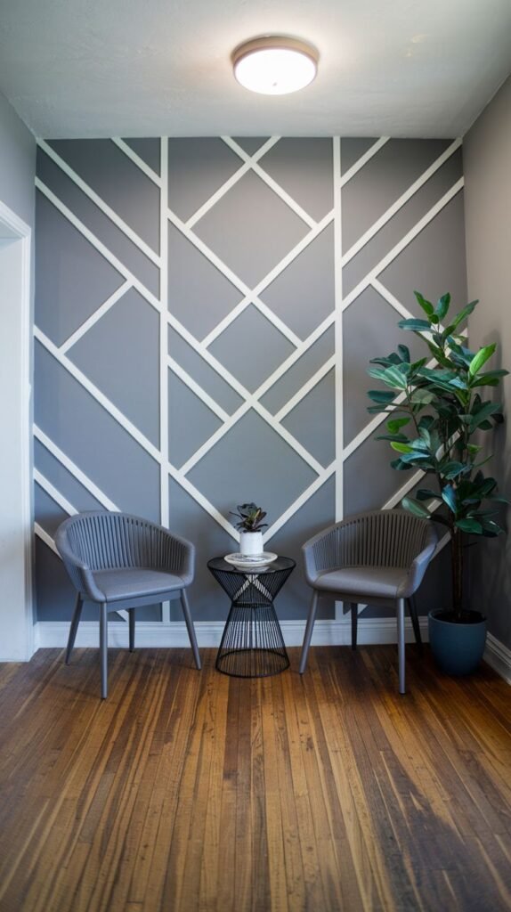 Entryway with gray walls featuring a geometric pattern created by white intersecting trim, two gray chairs, a black wire table, and a potted plant.