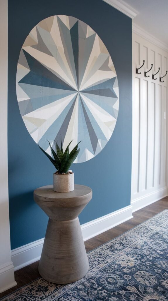 Deep blue accent wall featuring a large, central circular mural composed of radiating triangles in white, light gray, and blue tones, above a small gray pedestal table.