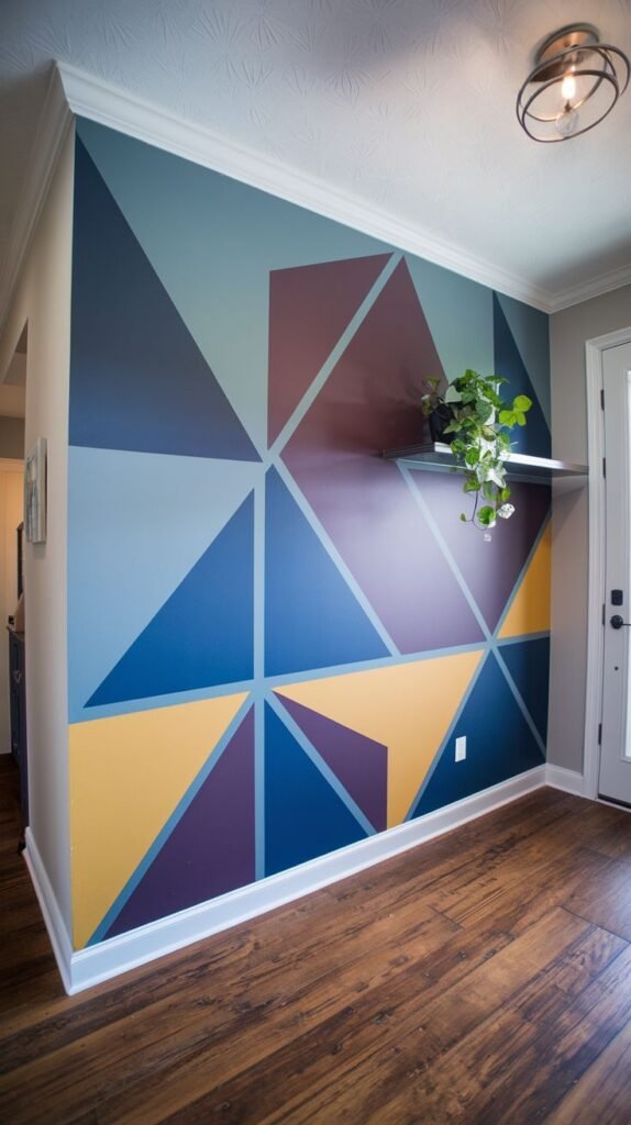 Bright entryway accent wall featuring a large, sharp geometric mural composed of interlocking triangles in shades of blue, purple, maroon, and yellow.