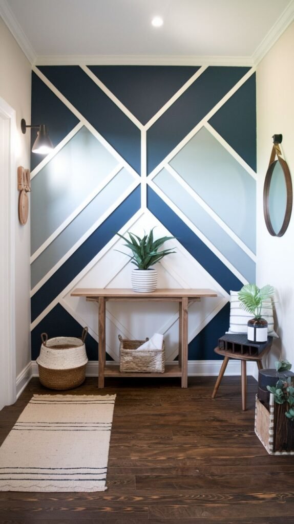 Entryway accent wall covered in a large-scale geometric pattern defined by white trim, with segments painted in navy, light blue, and gray, set above a wooden console table.