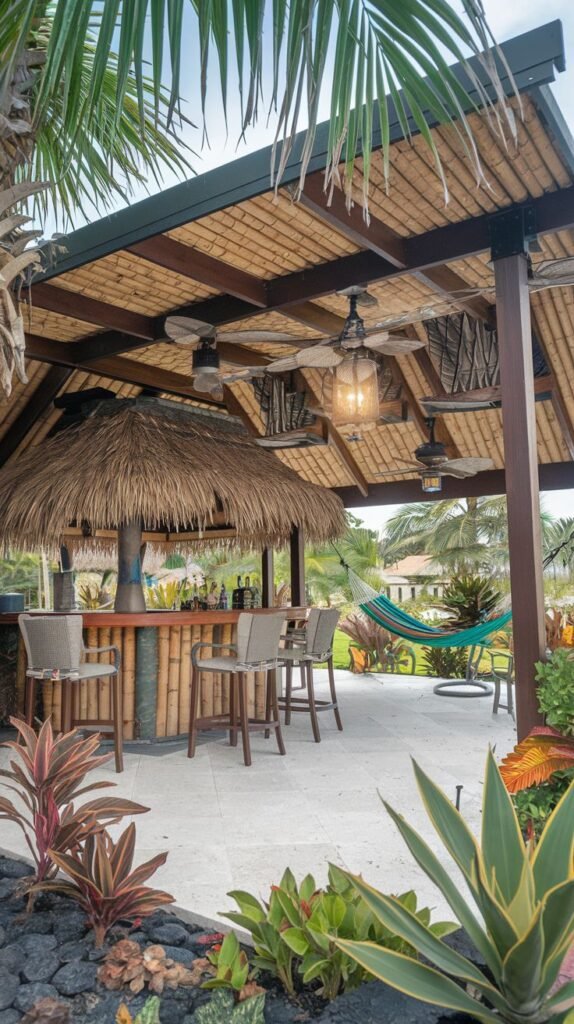 Tropical outdoor bar area with a thatched roof section and bamboo counter, a woven mat roof covering, and multiple ceiling fans surrounded by lush tropical plants.