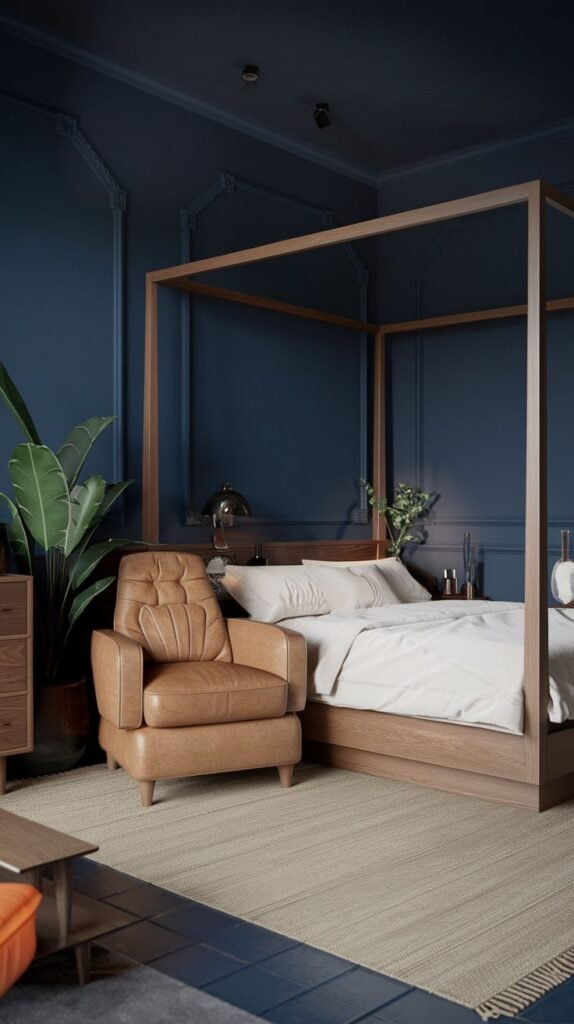 Japandi Small Bedroom with deep navy walls, a light wood four-poster bed frame, and a contrasting tan leather armchair on a beige rug.