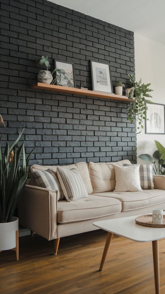 Textured black painted brick accent wall featuring a single, natural wood floating shelf displaying framed pictures and plants, above a beige sofa.