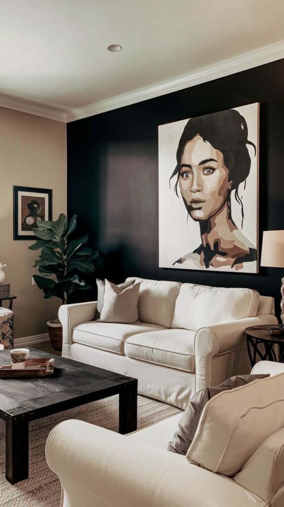 Living room with a matte black accent wall featuring a large modern portrait of a woman. The space includes two cream-colored sofas, neutral throw pillows, a dark wood coffee table, and a potted plant, creating a clean and contemporary look.