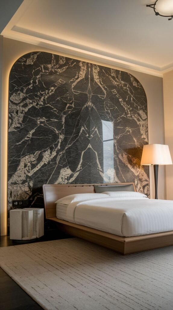 A bedroom featuring a dramatic, arched inset panel of dark marble with stark white veining, accented by perimeter lighting.