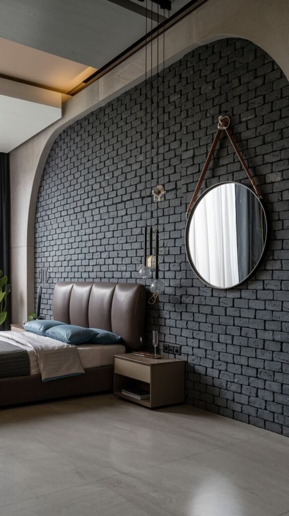 A bedroom featuring an arched recess covered in dark grey brick, serving as an accent wall with a round mirror suspended by a leather strap.