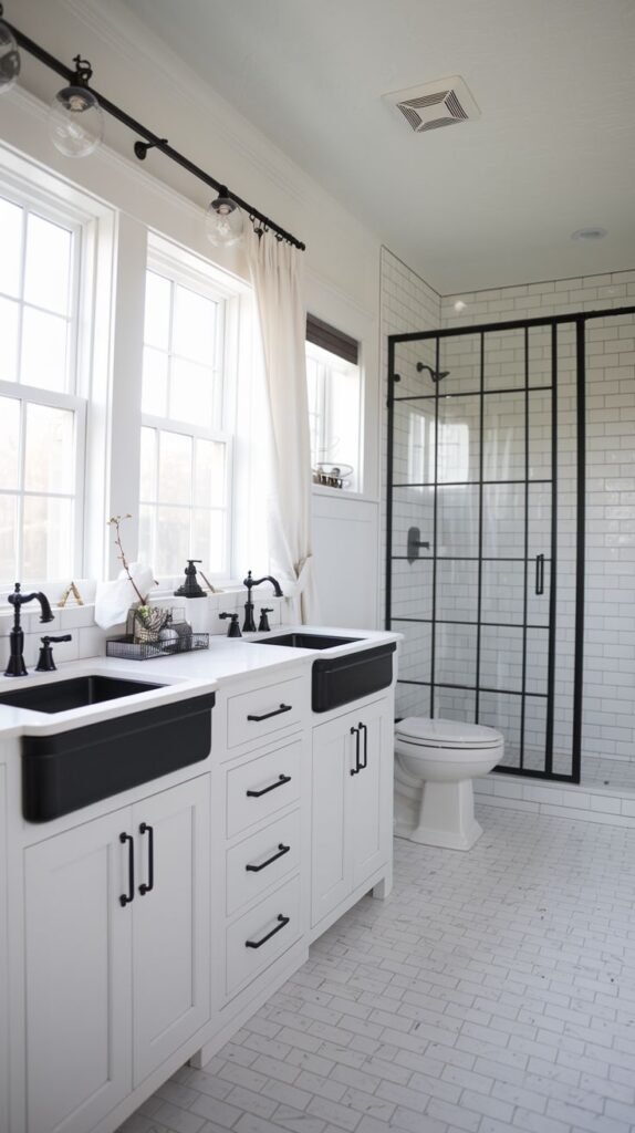 White vanity with dual black farmhouse apron sinks and black hardware, white subway tile walls, and a black grid frame glass shower door over white mosaic floor tiles in a bold Modern Farmhouse Master Bathroom.