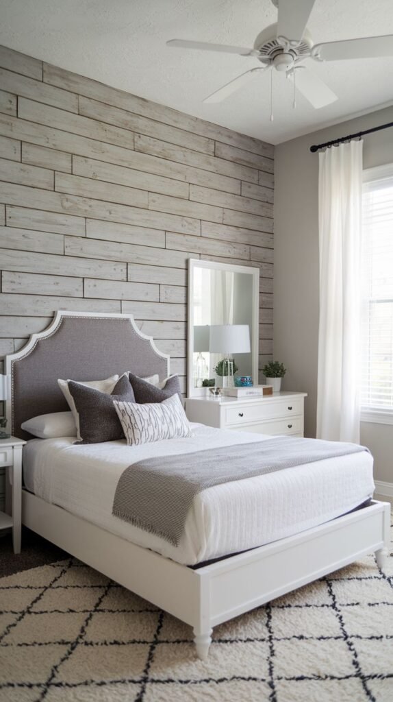 A bedroom featuring a white and gray bed set against an entire wall covered in weathered gray/bleached horizontal shiplap planks.