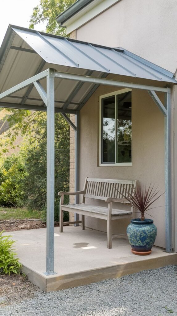 Simple covered concrete patio with an industrial-style metal gabled frame structure and metal roof. Features a wooden slatted bench and a large blue decorative pot.