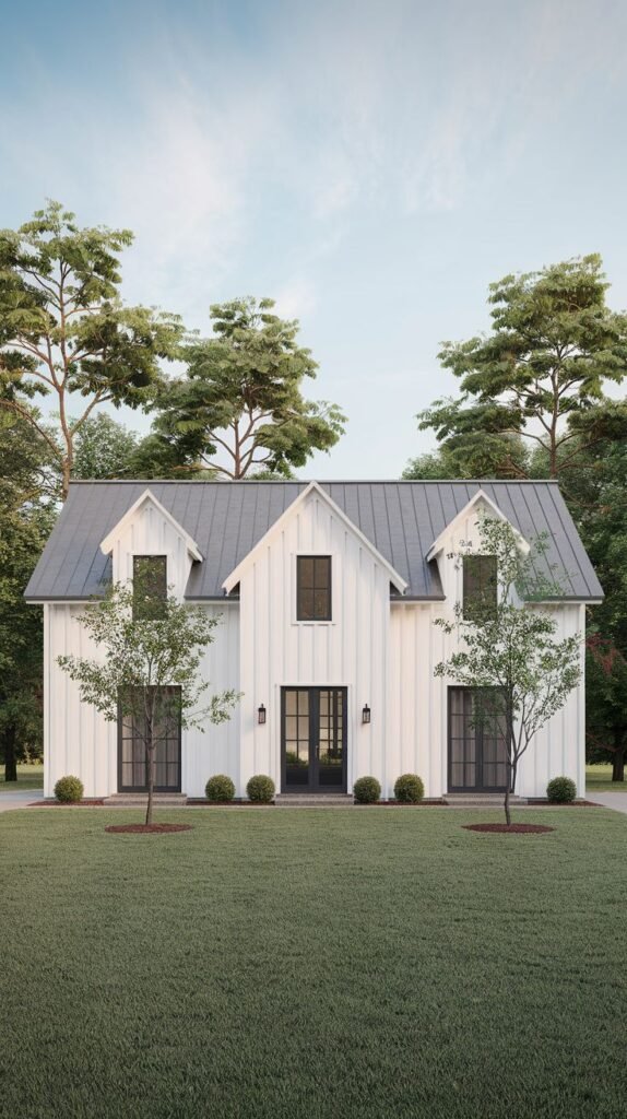 Symmetrical two-story white farmhouse with a dark gray metal roof featuring three dormers. The foreground is a neat green lawn flanked by tall pine trees, highlighting the central black door.