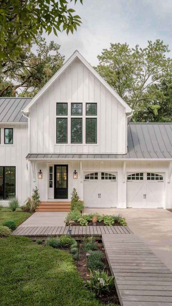 White modern farmhouse with a prominent central gable and an integrated two-car garage with arched doors. The entryway features a unique path composed of weathered wood decking and concrete leading toward the black front door.